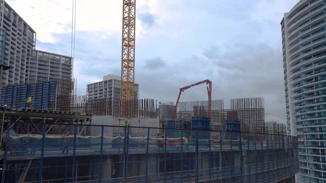 Construction workers building 35th floor of luxury high rise condominium skyscraper constructing core of structure in downtown Miami Florida USA  lots of unrecognizable people 