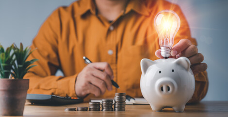 saving energy and money concept. idea for save or investment. businessman holding lightbulb on...