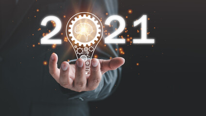 2021 goal, target business concept, hand of businessman with a light bulb And there is a gear icon...