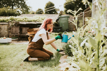 Happy female gardener watering plants © Rawpixel.com