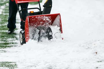 Man using a snow blower to remove large amounts of snow on football field. Man cleans snow with a...