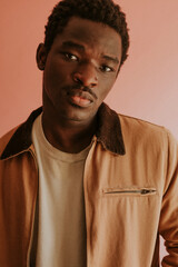 Obraz premium Black man in brown jacket mockup on pink background studio shot