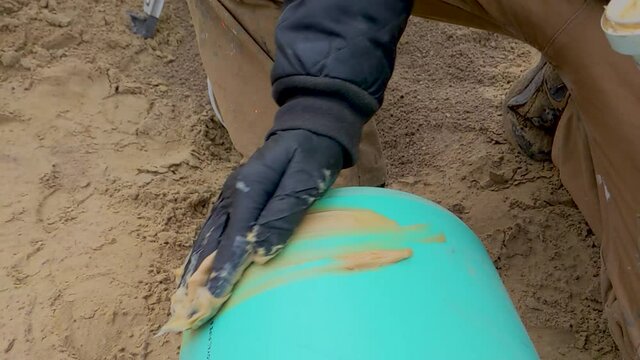 Construction worker spreading pipe lube / grease on the end of a sewer pipe in preparation for assembly.  Installing underground SDR gravity sewer pipe. Slow Motion