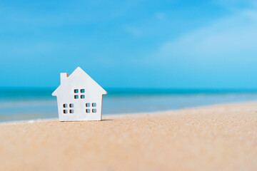 Closed up tiny home models on sand with sunlight and beach.