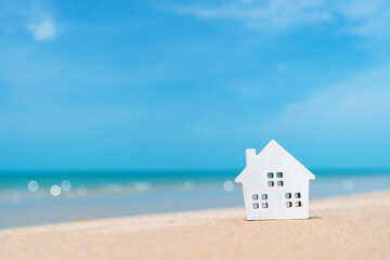 Fototapeta na wymiar Closed up tiny home models on sand with sunlight and beach.