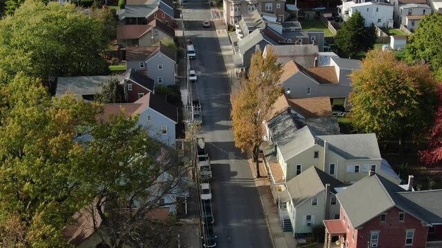 Aerial tilt up reveals two story homes in small town community neighborhood.  Cars on quiet street. Establishing shot in Northeast United States of America, USA.