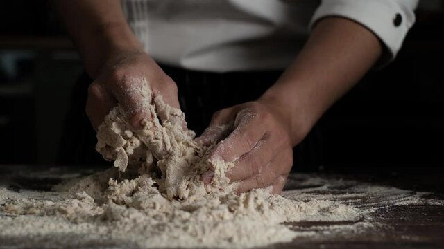 Slow Motion shot of  bakery chef kneeding dough on wooden table. Baking concept.