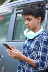 Indian Cute boy listening to music and using mobile phone