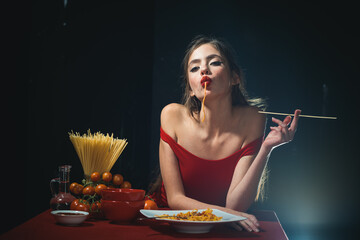 Young sexy woman eating tasty pasta on black.