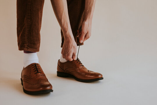 Man tying on brown leather shoes