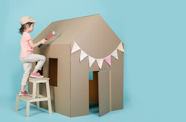 Asian little child girl building her cardboard house isolated on blue long banner with copy space for your text, Creative at home with family concept