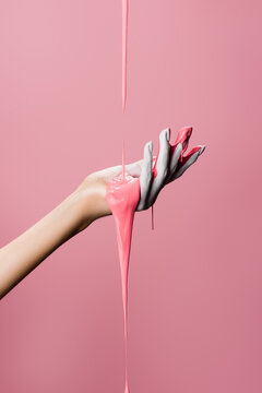 cropped view of hand with dripping paint isolated on pink, stock image