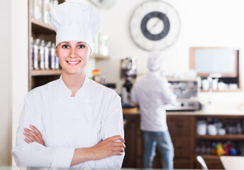 Bakery happy female worker with delicious pies and rolls on counter