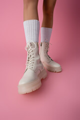 cropped view of female legs in boots and socks on pink 