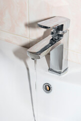 chrome faucet with running water, in the bathroom