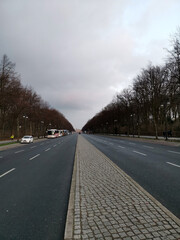 Fototapeta premium Long empty road in the winter to the brandenburger gate in berlin with parking tourist buses