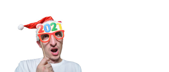 crazy man with stubble in a New Year's cap with glasses for a photo shoot 2021 is surprised at Christmas. happy holiday concept