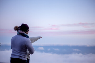 happy couple in sweaters hugging outdoor in snow day. The people above the clouds in the evening look at the blanket from the cloud
