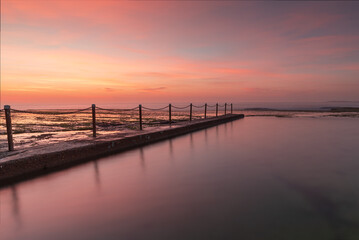 Fototapeta na wymiar Rock pool during the calm and colourful sunrise on the coast.