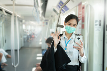 Fototapeta na wymiar New normal concept.Attractive asian business woman wearing face mask in the public metro during coronavirus pandemic.Woman wearing face shield and white shirt while business travel trip to the office.
