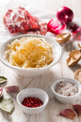 Ingredients for hearty sour cabbage soup (sauerkraut soup) with meat, onioc, garlic and spicies