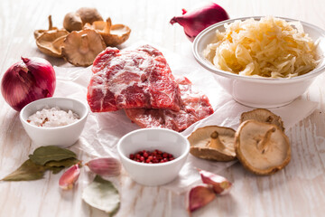 Ingredients for hearty sour cabbage soup (sauerkraut soup) with meat, onioc, garlic and spicies