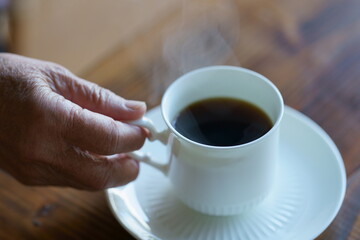 コーヒーを飲む高齢者の手元