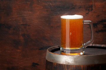 Mug of light lager beer and old wooden barrel