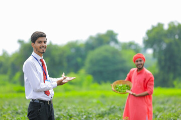 Young indian agronomist standing with farmer at green chilly field