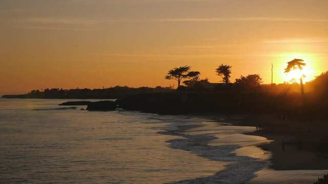 Santa Cruz California dog beach with sunset sky in silhouette, Pan left reveal shot