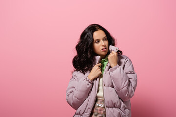  young woman in puffer jacket posing on pink background