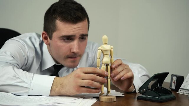 male office worker playing with wooden doll at work