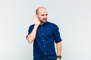 bald man looking serious and curious, listening, trying to hear a secret conversation or gossip,...