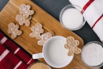 Fototapeta na wymiar Christmas Holiday Ginger Bread Man Cookie On Mug Of Milk With Cookies And Baking Material