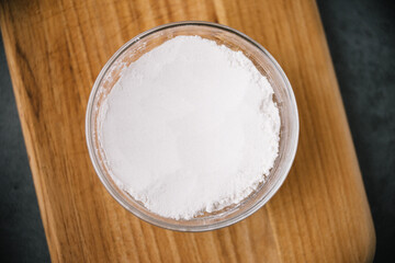 glass container of flour on wooden cutting board
