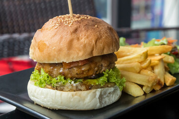 Beefburger  with crispy bacon, French fries and salad