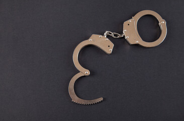 Metal handcuffs on an isolated black background.