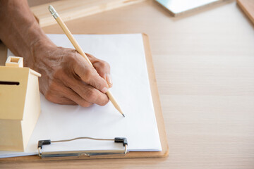 Close up senior asian old elderly man hand holding pencil for writing on paper to lecture or take note in wood carpenter concept