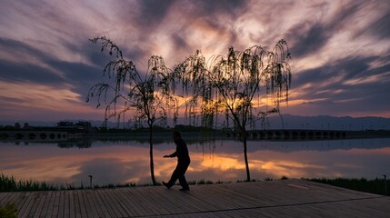 A man performing Tai chi on sunset during a rough weather.