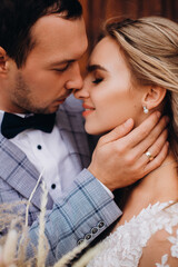 Portait of a newlywed couple in natural light. Groom in elegant suit gently hugs a beautiful bride with a closed eyes