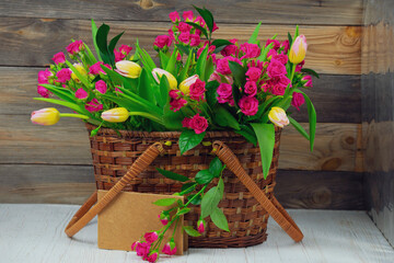 Fototapeta na wymiar beautiful bouquet of flowers, red rose and tulips in a wooden basket 