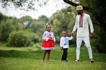 Obraz premium African father with kids in traditional clothes at park.