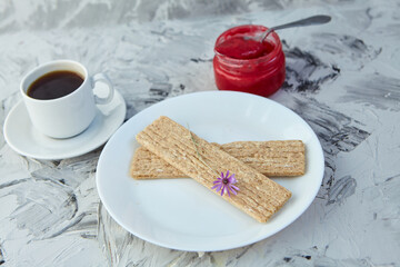 Crispbread with jam for Breakfast on a gray background. A jar of Fresh Honey with foam is next to a...