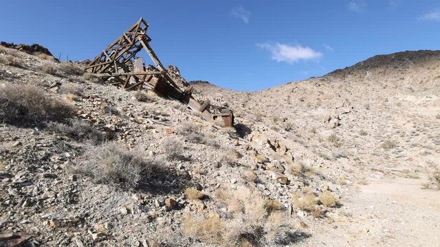 Pan left mining claim ore shaft and wood head frame built into desert mountain