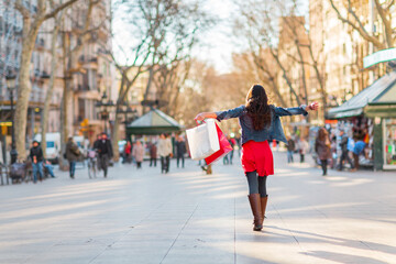 Happy shopping woman walking with bags on Barcelona, La Rambla famous street. Shopper with open arms up in freedom and happiness. From the tourist landmark in Catalonia, Spain. - obrazy, fototapety, plakaty