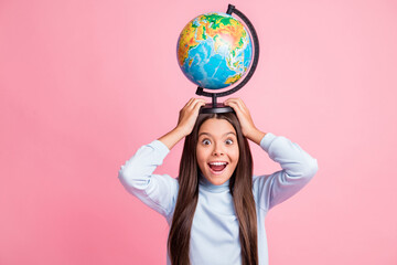 Portrait of pretty cheerful amazed funny girl carrying globe on head having fun isolated over pink pastel color background
