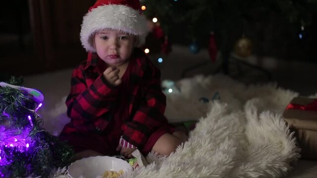 a child in red clothes is sitting waiting for the new year. the concept of celebrating Christmas at midnight. holiday costume