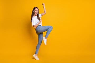 Fototapeta na wymiar Photo portrait full body view of excited woman with raised fists on one leg celebrating isolated on vivid yellow colored background