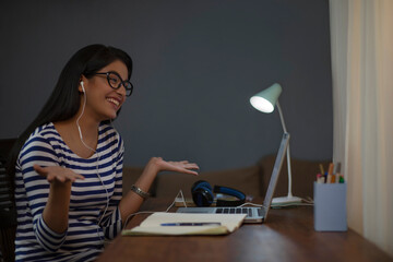 Girl talking on a video call late at night while completing her assignment	