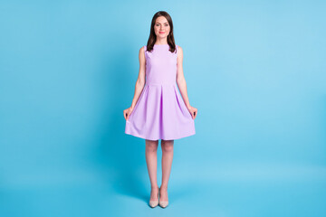 Full size photo of attractive peaceful cute young woman hold bottom of violet dress isolated on blue color background